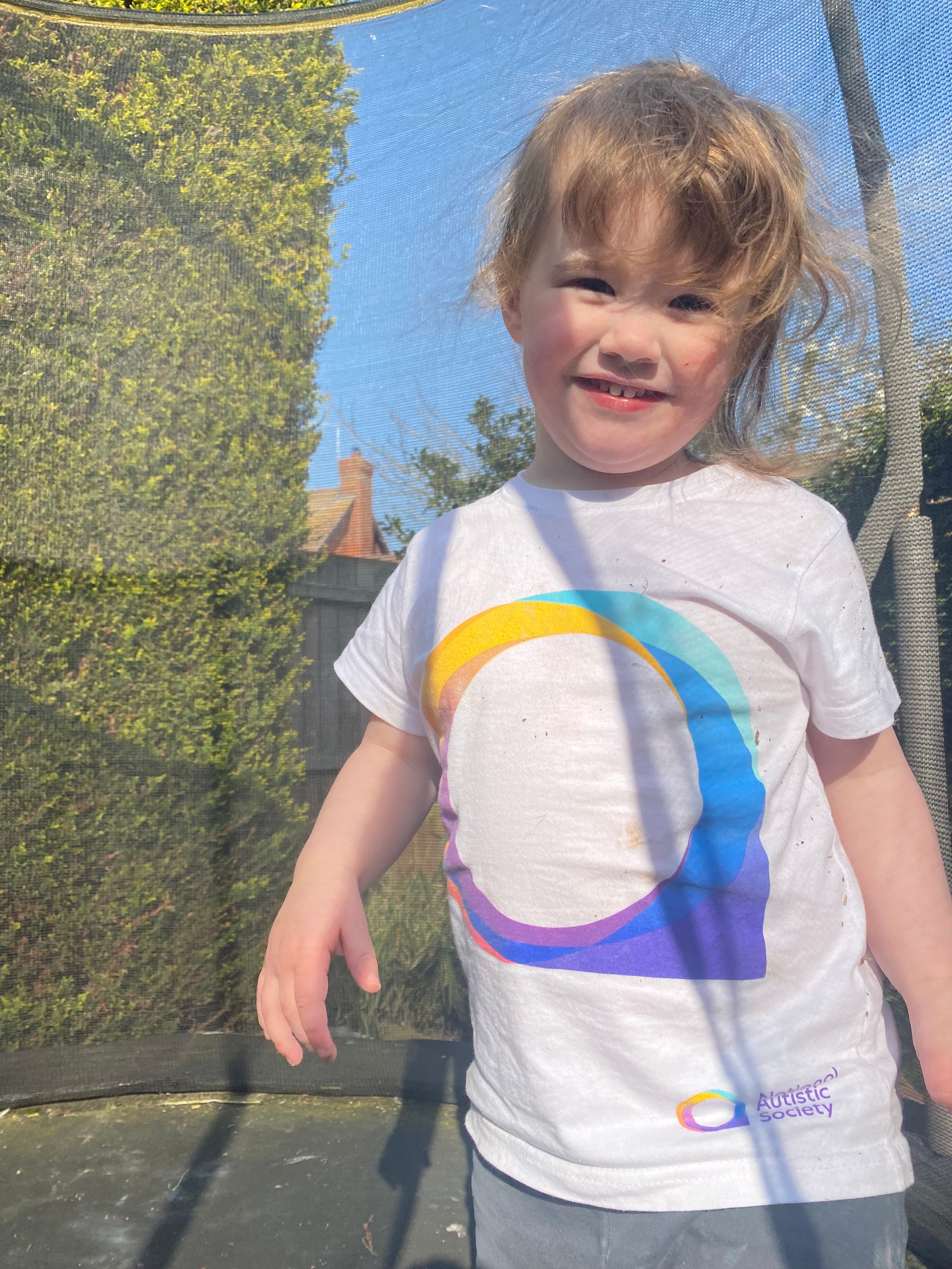 Picture of  Alice as a toddler on a trampoline wearing National Autistic Society T shirt.