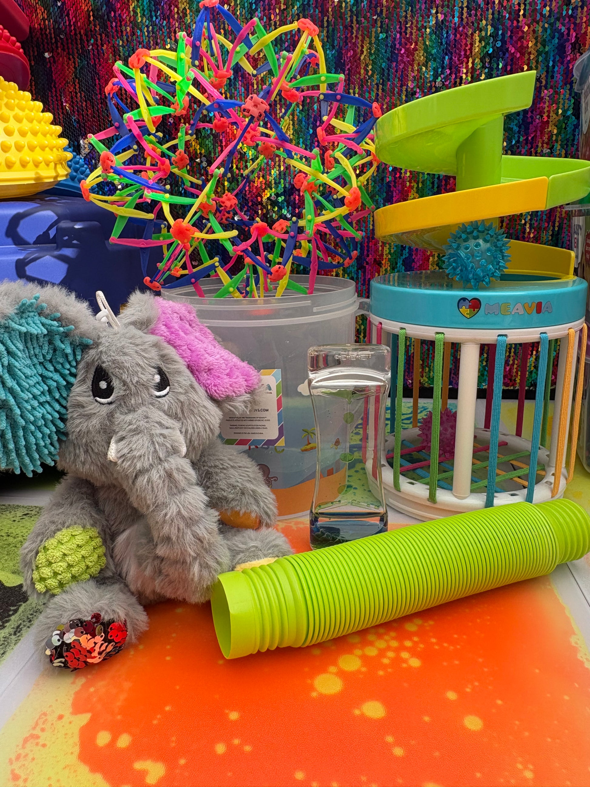 Colorful pet toy set with a small gray plush toy on a multicolored background