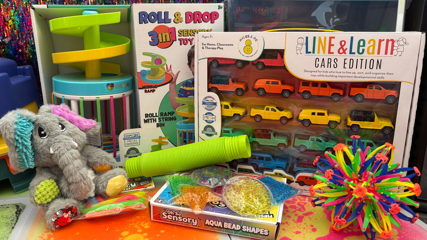 Assorted children's toys and educational materials on a colorful surface with a textured wall background.